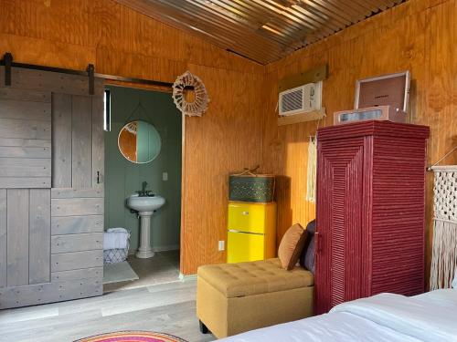 a bedroom with a red bed and a chair and a sink at En Suite Flora in Dripping Springs