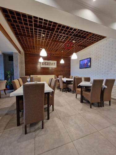 a dining room with tables and chairs and a tv at Hotel Djerdan in Kraljevo