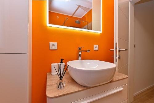baño con lavabo blanco y pared de color naranja en Apartment Luka 1481, en Medulin