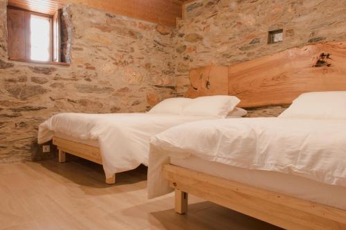 two beds in a room with stone walls at Casa Do Peirão 