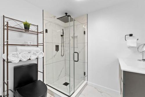 LUX White Marble Retreat near NYC في بايون: دش زجاجي مع كرسي أسود في الحمام