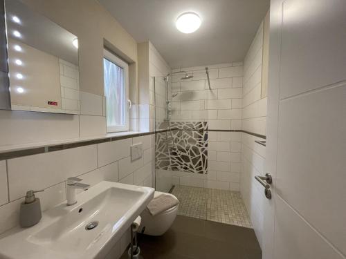 a white bathroom with a sink and a toilet at Ferienhaus Eichhörnchen in Zossen