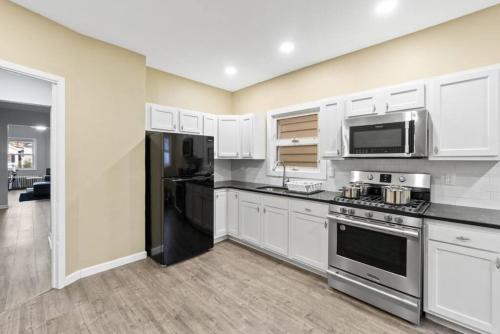 a kitchen with white cabinets and stainless steel appliances at Urban Duplex NWR NYC GAMES in Bayonne