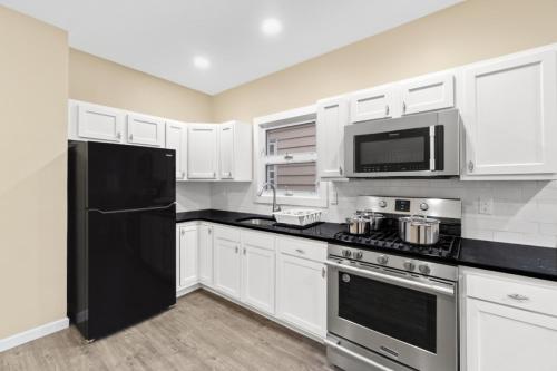 a kitchen with white cabinets and a black refrigerator at Urban Duplex NWR NYC GAMES in Bayonne