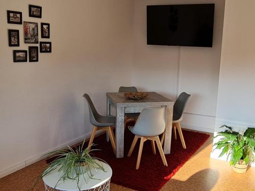 a table with four chairs and a television on a wall at Ferienwohnung Wiesenblick in Illingen