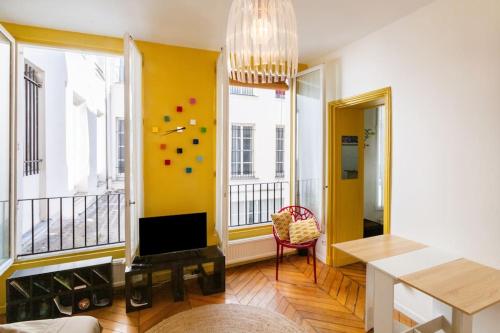 d'un salon avec des murs jaunes et un lustre. dans l'établissement Charming Studio - Saint Apoline, à Paris