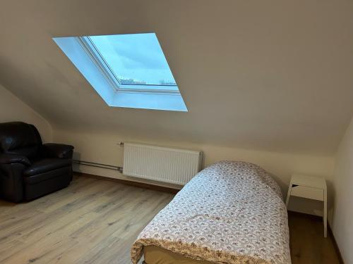 a bedroom with a skylight and a couch and a chair at Trietje in Ghent