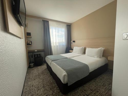 a hotel room with a bed and a window at Sure Hotel by Best Western Bordeaux Lac in Bordeaux