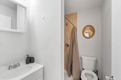 uma casa de banho com um WC, um lavatório e um espelho. em Whimsical three em Bayonne