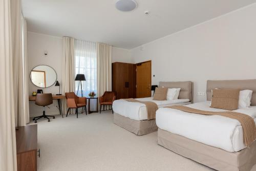 una camera d'albergo con 2 letti e una scrivania di The MANOR Sports & Spa a Tõrva