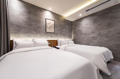two beds in a room with white sheets at Sokcho Business Hotel CAMEL in Sokcho