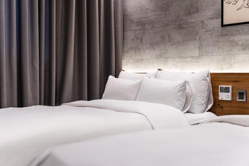 two beds with white pillows in a bedroom at Sokcho Business Hotel CAMEL in Sokcho