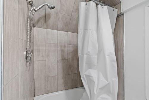 a shower with a white shower curtain in a bathroom at Whimsical Two in Bayonne