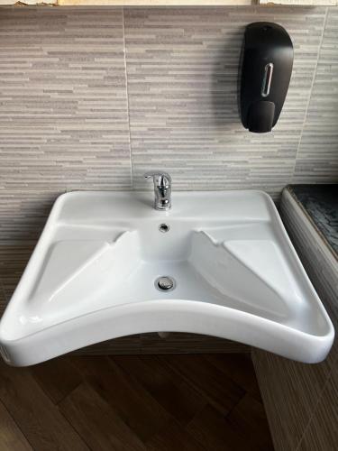 a white sink in a bathroom with a phone on the wall at Gloria Hostel Milano in Milan