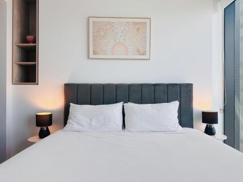 een slaapkamer met een bed met witte lakens en 2 lampen bij Eyes on the Fireworks Lux Riverfront 2KingBed Apt in Brisbane