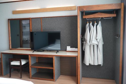een slaapkamer met een bureau, een tv en een spiegel bij Sacheon Grand Tourist Hotel in Sacheon