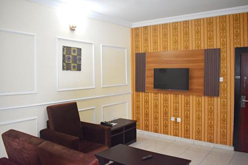 a living room with a couch and a television on a wall at DAVIS HOTEL AND SUITES in Port Harcourt