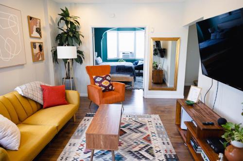 a living room with a yellow couch and orange chairs at Rainforest Retreat 20m to NYC Parking Sleeps 25 in Bayonne