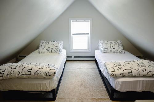 two beds in a attic room with a window at Rainforest Retreat 20m to NYC Parking Sleeps 25 in Bayonne