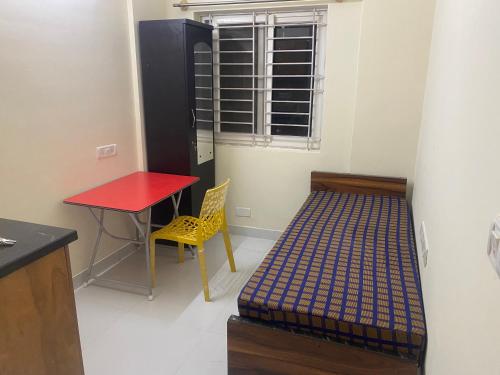Zimmer mit einem Bett, einem Tisch und einem Schreibtisch in der Unterkunft SSV stays in Bangalore