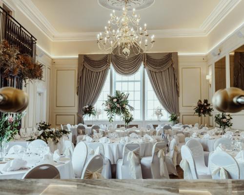 a banquet hall with white tables and chairs and a chandelier at The Kings Arms Hotel in Berwick-Upon-Tweed