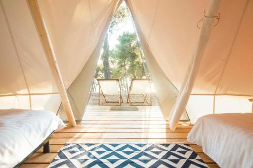 a room with a tent with two beds and a rug at O-Tents by Obonjan in Šibenik