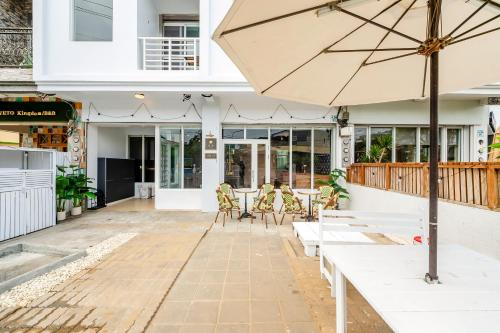 a patio with tables and chairs and an umbrella at H& Sunset Mu Style Inn in Xiaoliuqiu