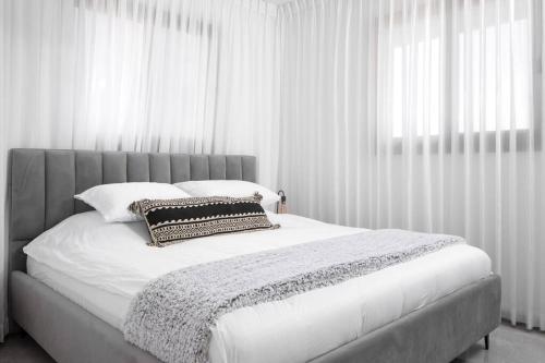 um quarto branco com uma cama grande e cortinas brancas em סוויטה מרווחת, רומנטית ומפנקת em Eilat