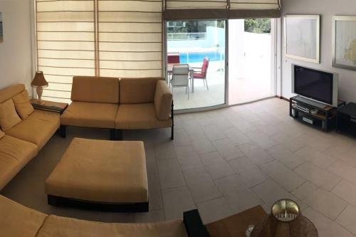 uma sala de estar com um sofá e uma televisão em Chalet en C.Vadella - Piscina privada em Cala Vadella