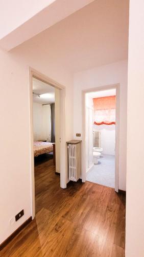 Habitación con paredes blancas, suelo de madera y 1 dormitorio. en Casa Natale, en Pralungo