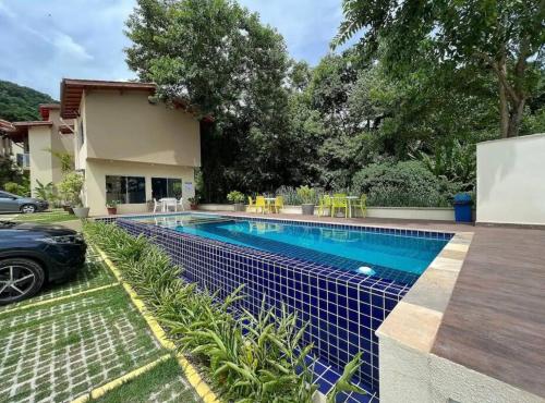 a pool in a backyard with a car parked next to it at Linda Casa em uma linda praia - Santiago/ Maresias in São Sebastião