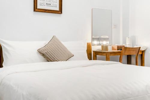 a bedroom with a white bed and a table at Sunset Mu Style Inn in Xiaoliuqiu