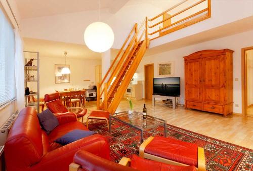 una sala de estar con muebles de cuero rojo y una escalera en Wohnung 22, en Ostseebad Karlshagen