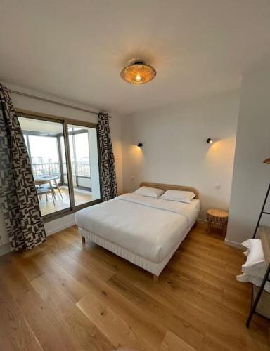 ein Schlafzimmer mit einem weißen Bett und einem großen Fenster in der Unterkunft Penthouse / 2 bedrooms in city center of Angers in Angers