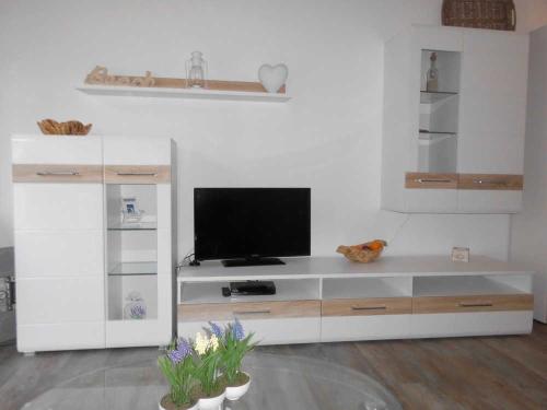 um centro de entretenimento branco com uma televisão numa sala de estar em Wohnung 59 em Ostseebad Karlshagen