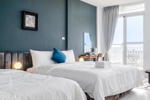 two beds in a bedroom with blue walls at H& Sunset Mu Style Inn in Xiaoliuqiu