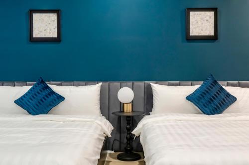 a bedroom with two beds and a blue wall at Sunset Mu Style Inn in Xiaoliuqiu