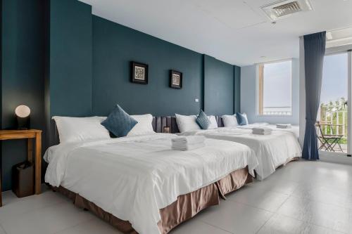 two large beds in a room with blue walls at Sunset Mu Style Inn in Xiaoliuqiu