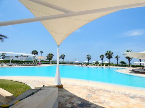 duży basen z białym parasolem w obiekcie Casa de Playa Deluxe en Condominio Playa Coral w mieście Fundo Copacabana