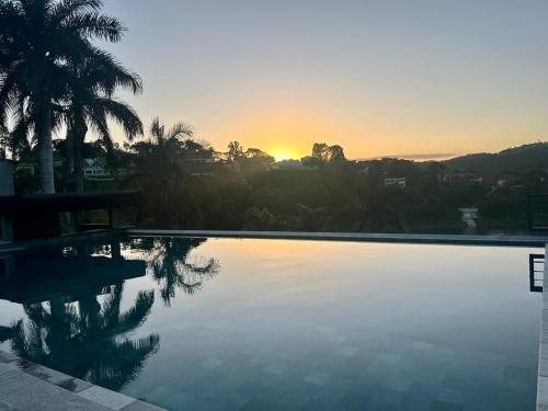 une grande piscine avec un coucher de soleil en arrière-plan dans l'établissement Pousada Villa Shalom, à Igaratá