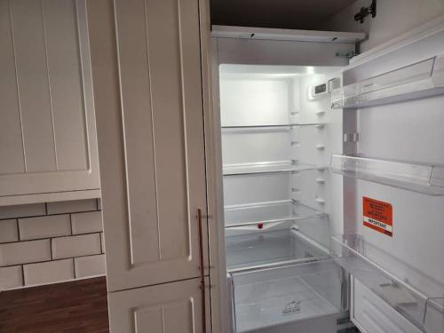 an empty refrigerator with its door open in a kitchen at Comfy Guest House in London