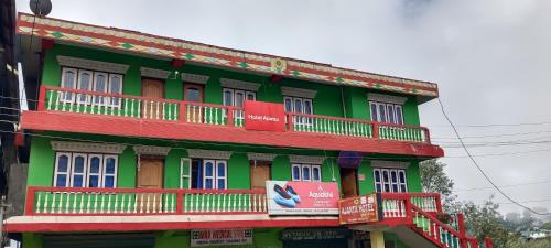 a green and red building with balconies on it at Aajanta in Tawang