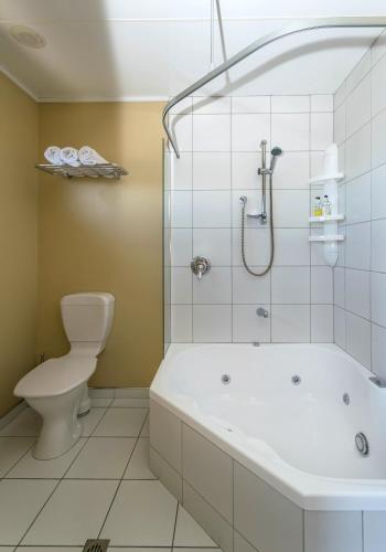 a bathroom with a shower and a toilet and a tub at Blenheim Spa Motor Lodge in Blenheim