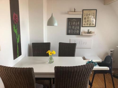 a dining room table with chairs and a vase of flowers on it at Ferienwohnung Zeitlos in Gundelsheim
