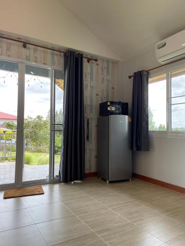 a room with a refrigerator in a room with windows at บ้านไร่โฮมเทล ณ ปากช่อง in Ban Nong Takhain