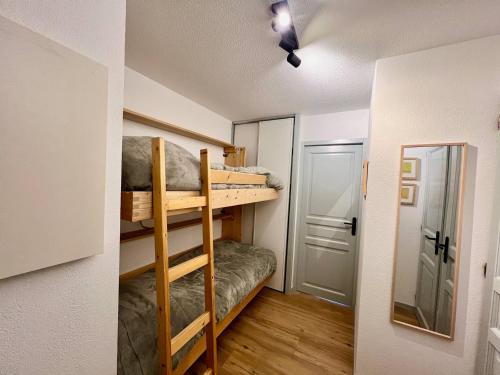 Cette petite chambre comprend des lits superposés et un miroir. dans l'établissement Appartement cosy 4 pers. à Valloire, proche centre & pistes, balcon, parking, casier à skis - FR-1-263-529, à Valloire