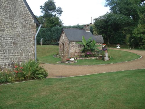 une maison en pierre avec un jardin dans une cour dans l'établissement Les Basses Rouves Niort, à Lassay