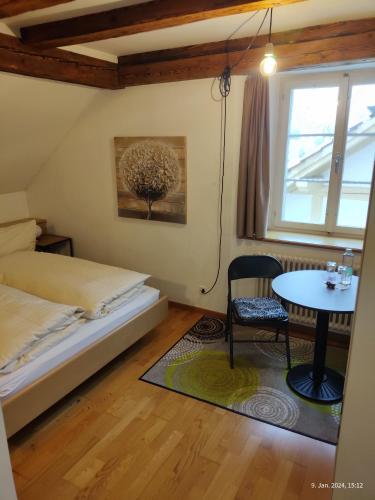 1 dormitorio con cama, mesa y ventana en Gasthaus "Hotel Hirschen", en Beromünster
