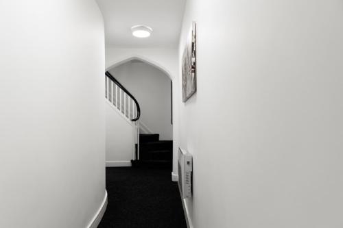 a hallway with white walls and a stair case at Vault Chambers in Brierley Hill