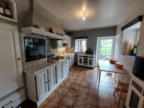 une grande cuisine avec des placards blancs et une télévision dans l'établissement Charmante maison de campagne, à Saint-Maurice-sous-les-Côtes